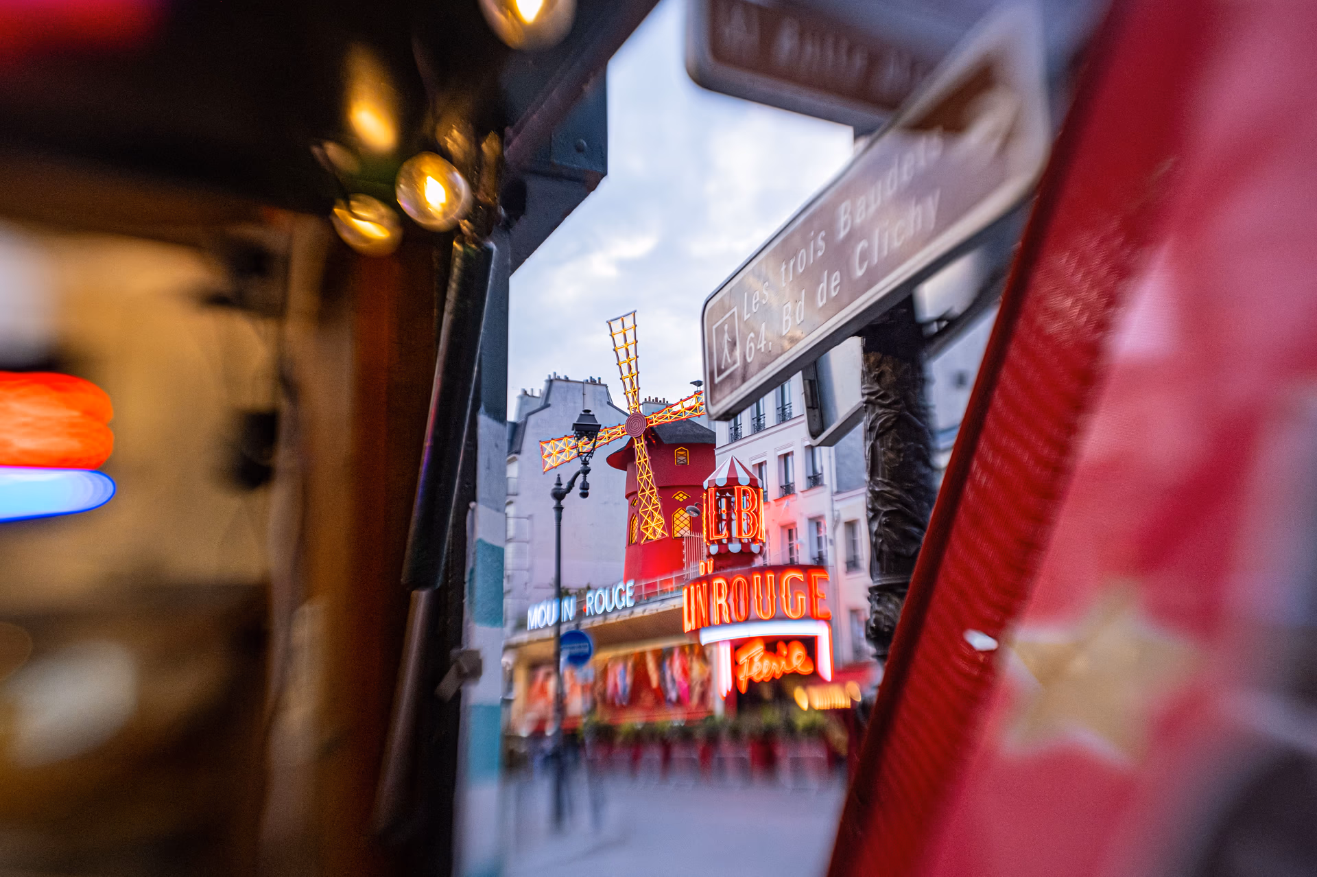 Vista del Moulin Rouge en París entre elementos rojos desenfocados en primer plano — Fujifilm X-E4 con Lensbaby Sweet 22