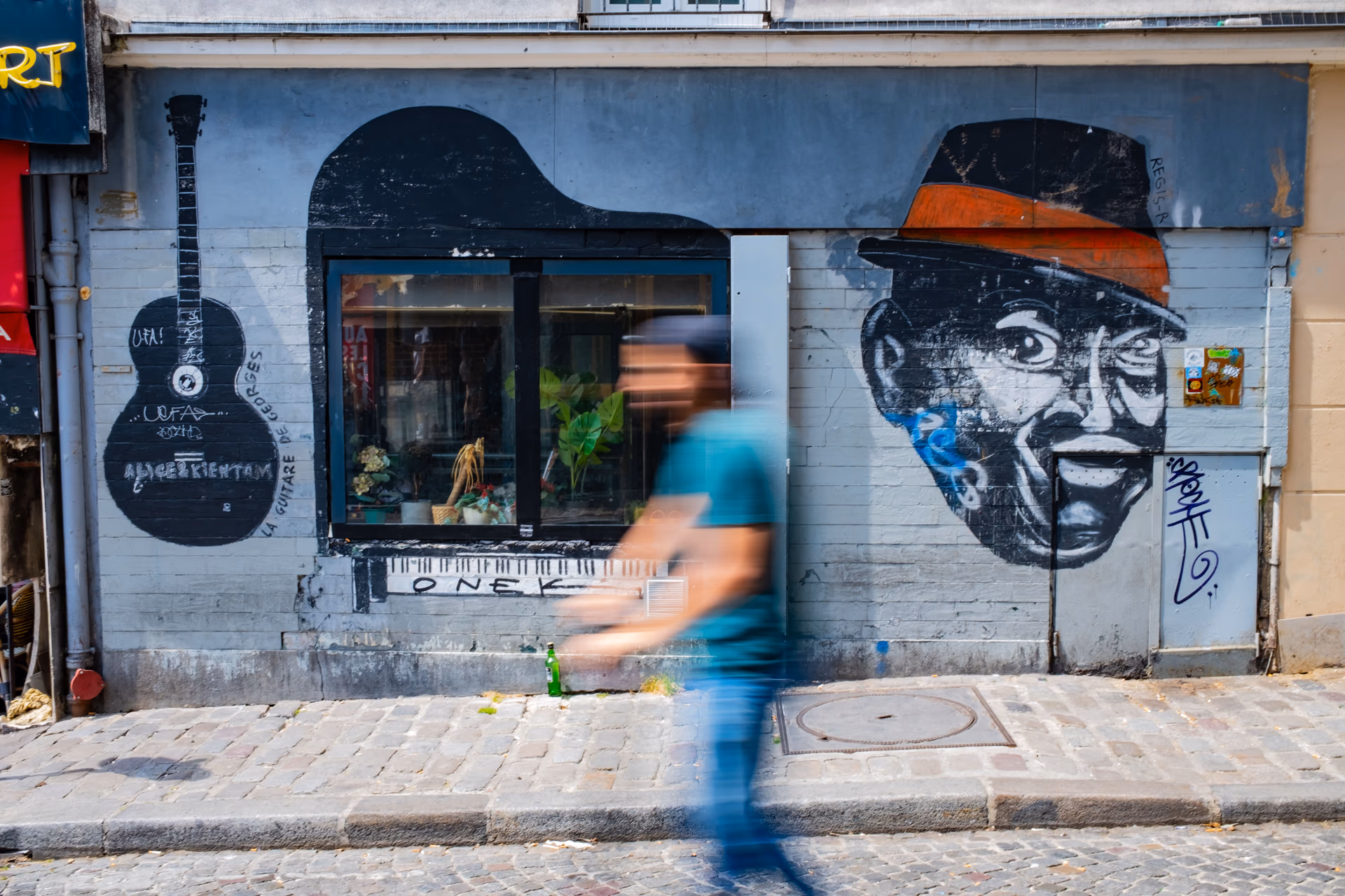 Arte urbano en una fachada de París con graffiti y street art, persona con camisa azul caminando — Fujifilm X100V