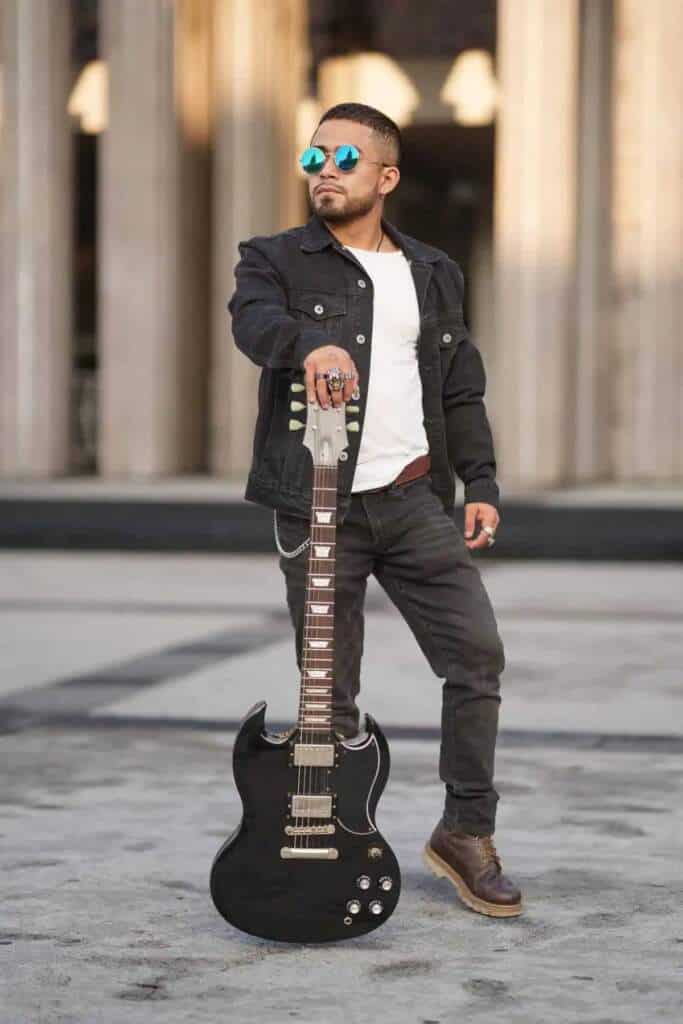 Hombre con guitarra y gafas de sol, con un tono amarillento que evoca el filtro México en el cine.