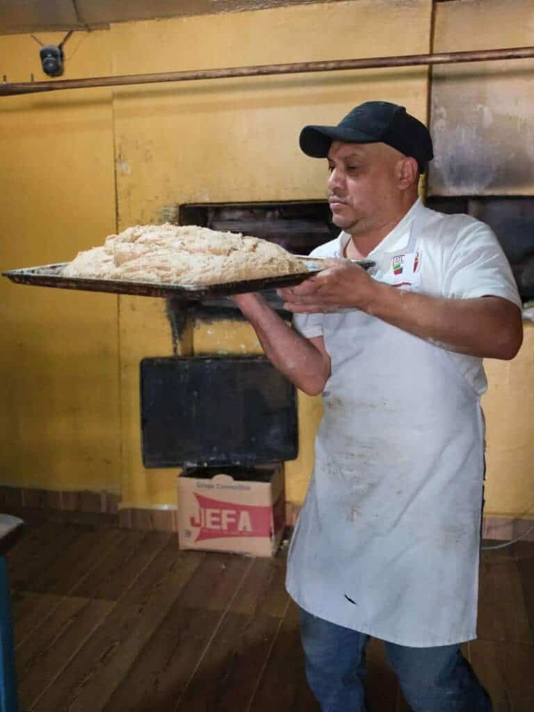 Panadero con charola de masa en panadería mexicana artesanal de Metepec.