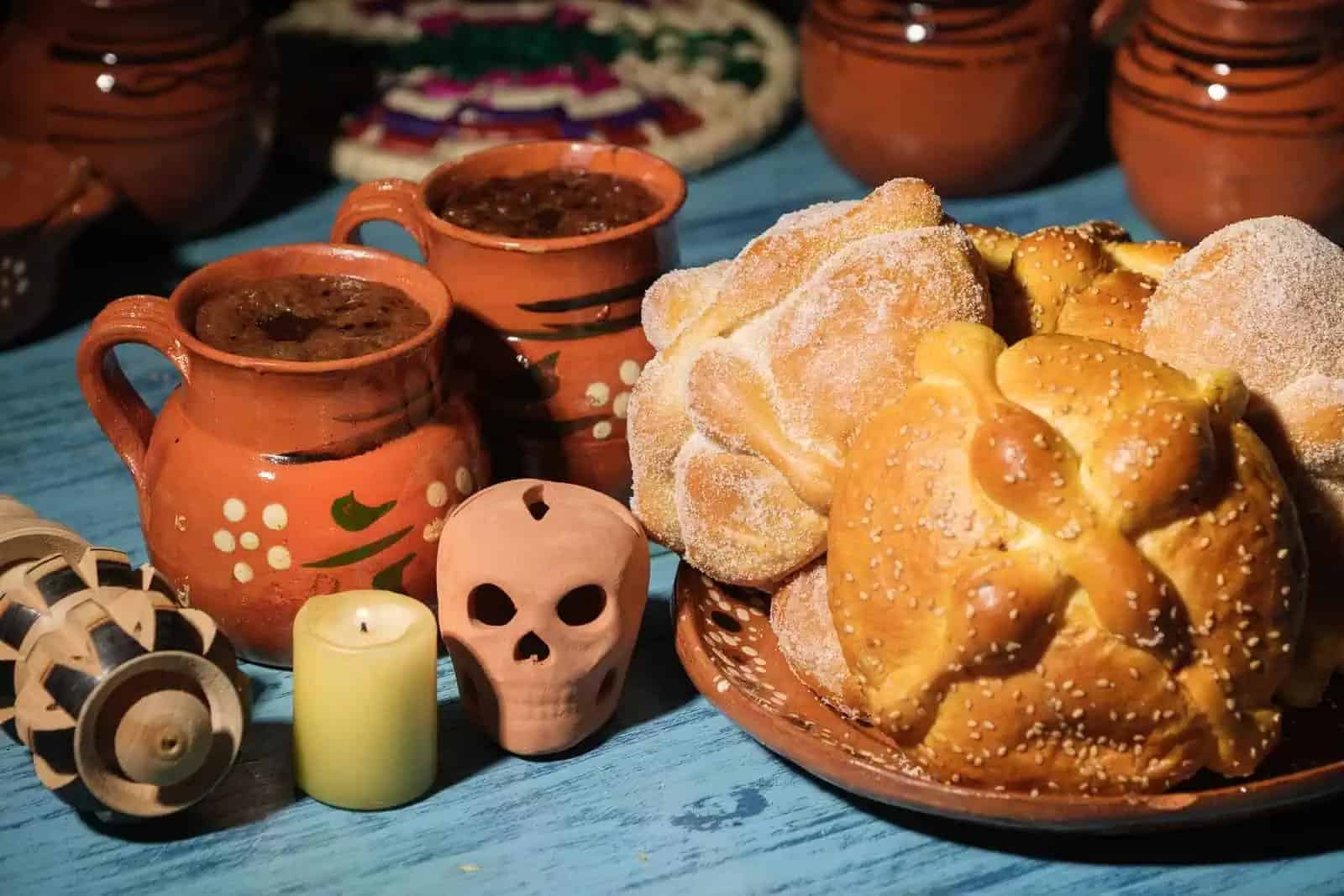 Pan de muerto y chocolate en taza de barro, fotografía de reportaje.