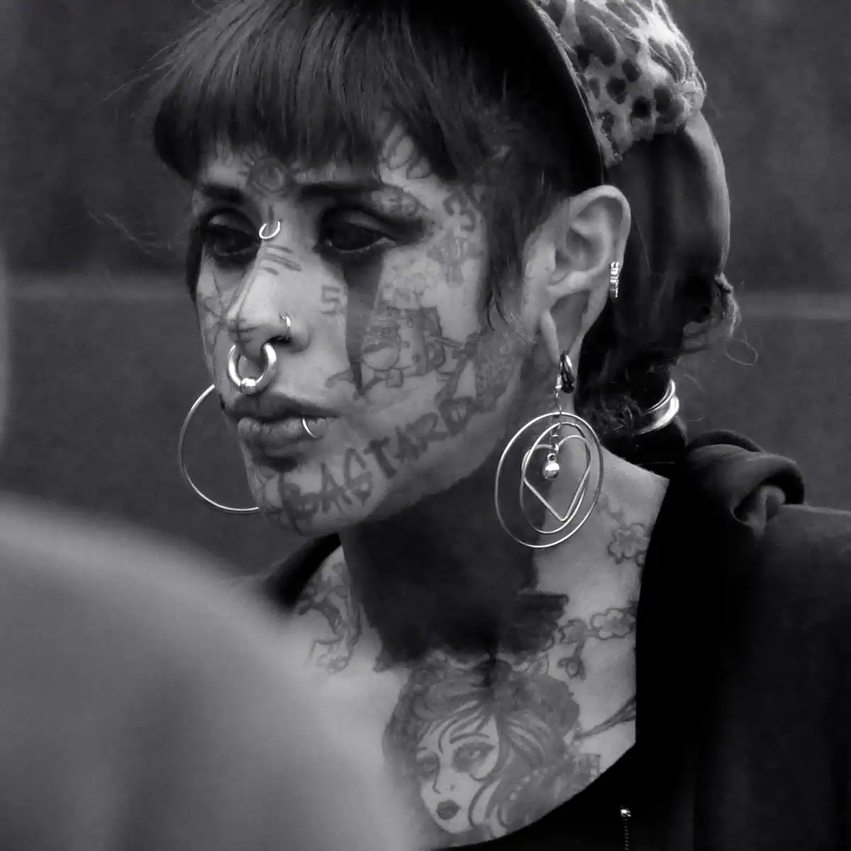 Retrato de una mujer tatuada con piercings en la nariz y aretes grandes, ejemplo del estilo documental de Jacob Prado