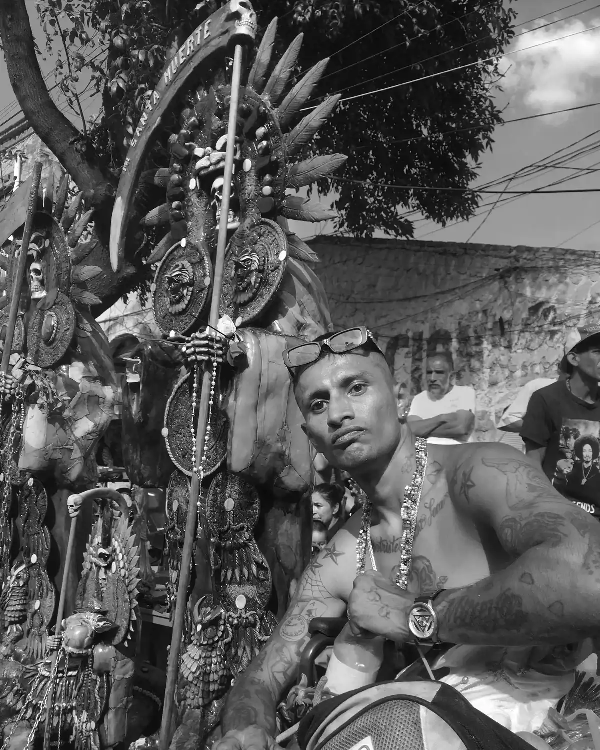 Hombre con tatuajes y joyas ante el altar de la Santa Muerte
