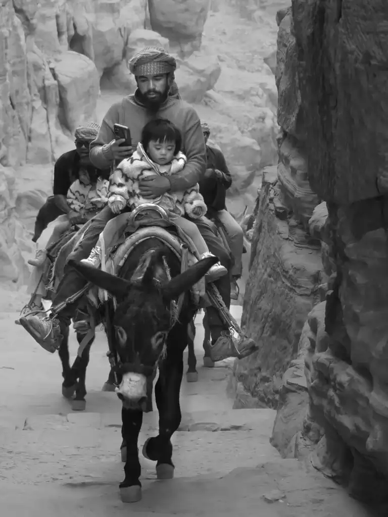 Hombre con un niño montado en un burro en un desfiladero, Jordania