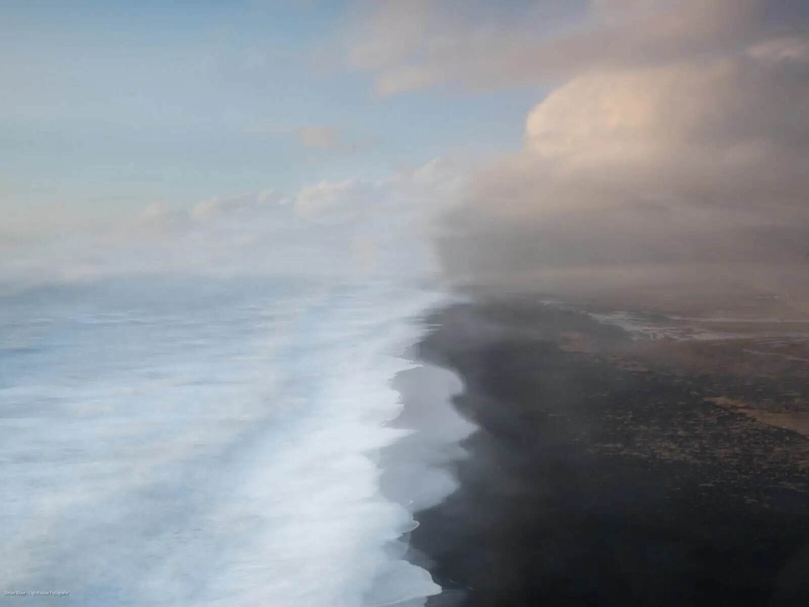Playa de arena negra con olas rompiendo y cielo nublado, fotografía como forma de omitir.