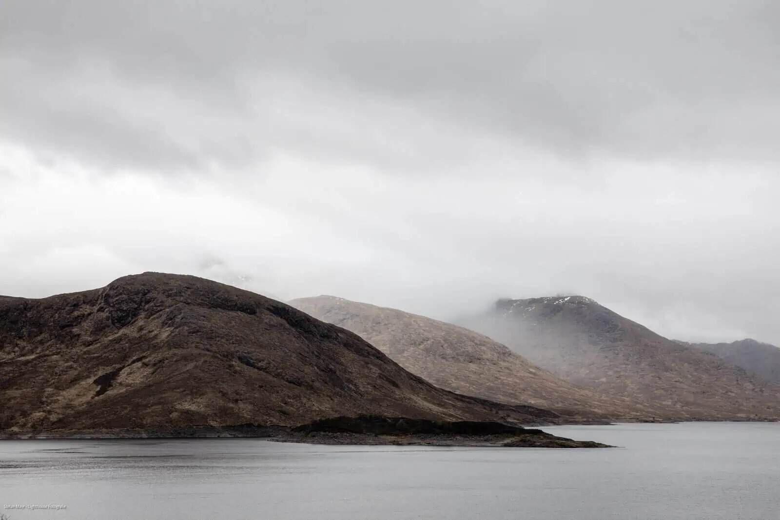 Montañas cubiertas de niebla sobre un lago, fotografía como forma de omitir.