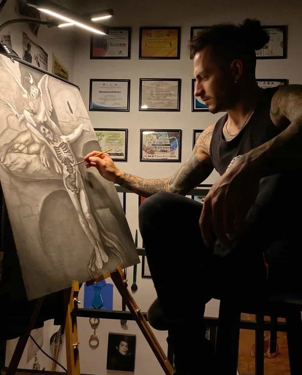 Armando Montes pintando una obra de arte con temática de esqueleto y alas