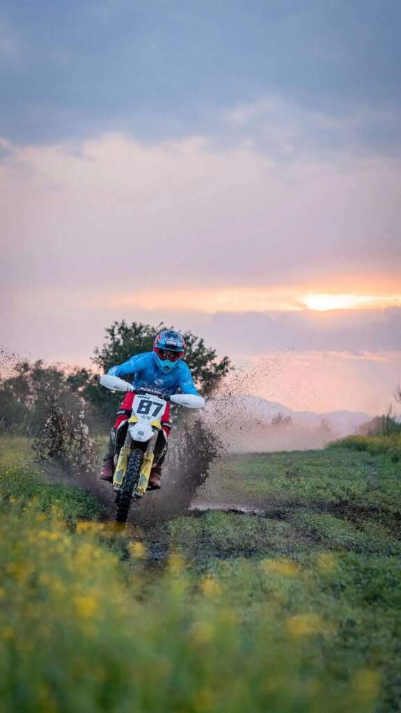 Ciclista de motocross salpicando lodo al atardecer, arte y deporte combinados.