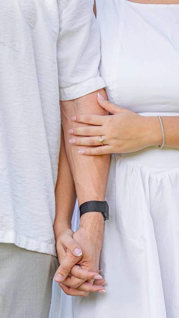 Pareja tomados de la mano, ella luce anillo de compromiso y pulsera