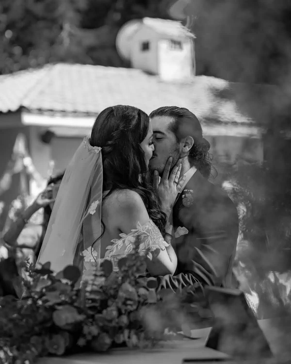 Pareja besándose apasionadamente, ella con velo de novia y él con traje.