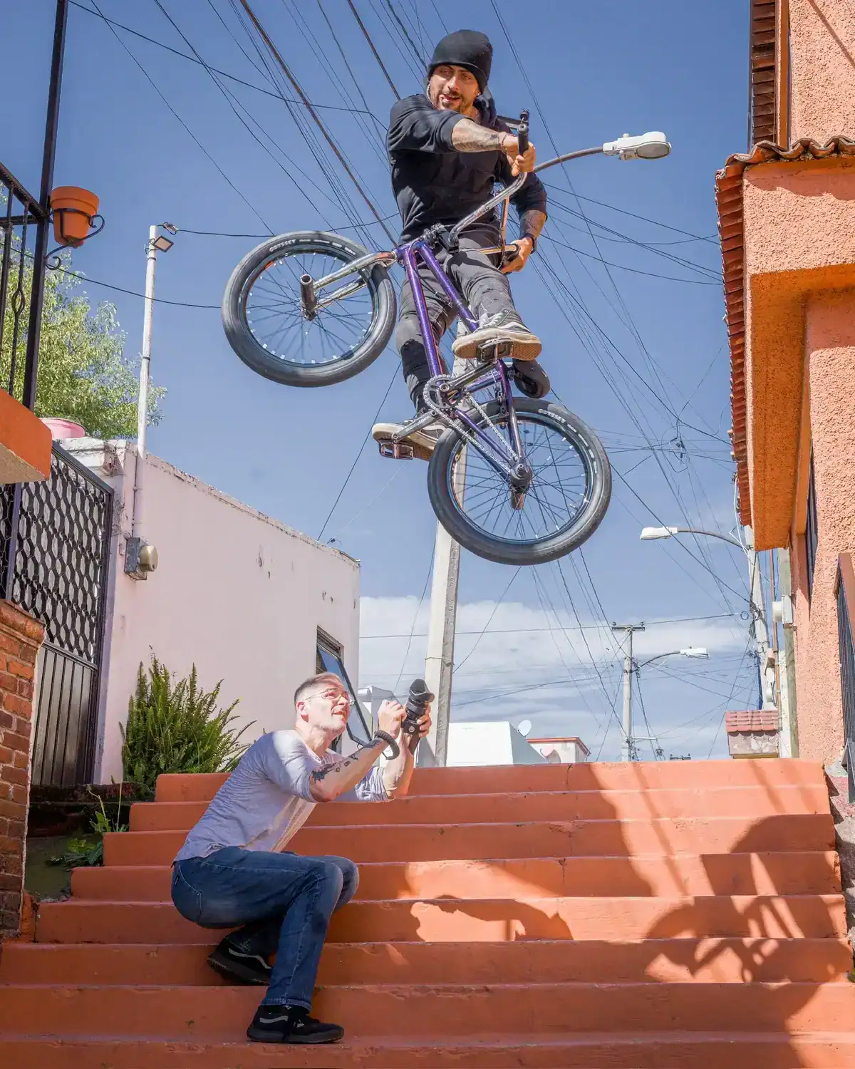 Fotógrafo captura a ciclista de BMX en salto aéreo sobre escaleras.