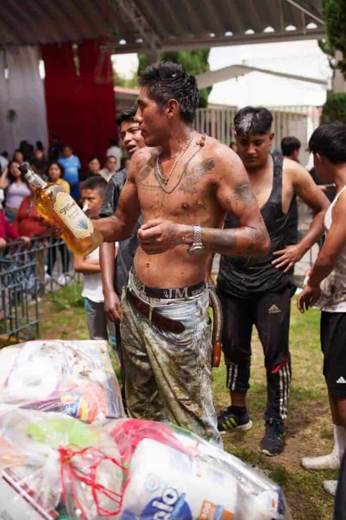 Hombre con botella de tequila en fiesta de palo encebado en Tlaxcala.