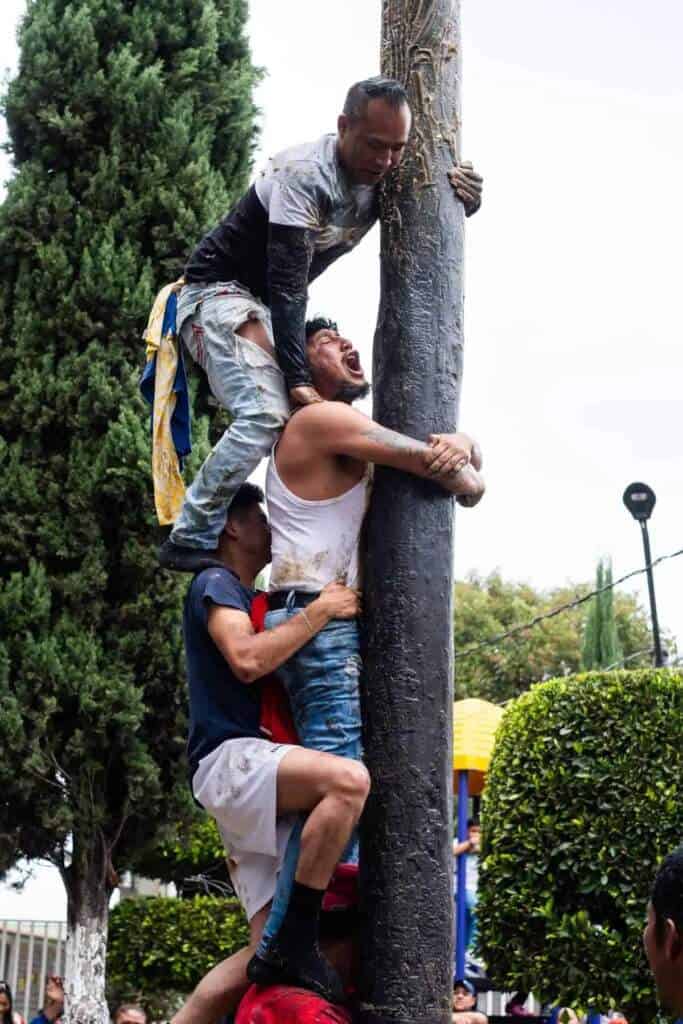Hombres escalando un palo encebado en Tlaxcala durante una tradición.